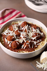 READY TO SERVE FAMILY-STYLE SPAGHETTI AND MEATBALLS  WITH A STACK OF PLATES AND FORKS