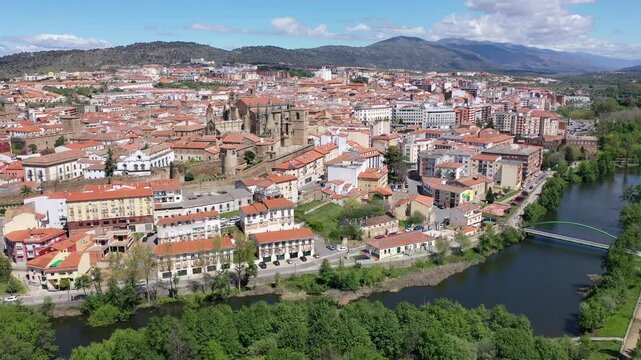  Bird's eye view of residential buildings with tiled roofs, Jerte River and cathedral in Plasencia, Extremadura, Spain. 