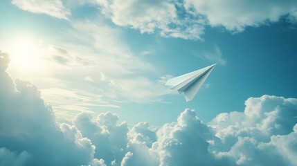 Fototapeta premium 14.A single white paper airplane soaring through the open sky, surrounded by fluffy white clouds and soft sunlight, with a gentle sense of movement suggesting it is gliding smoothly.