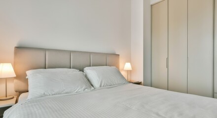 Fototapeta premium Minimalist bedroom with neutral tones, white bedding, and soft lighting