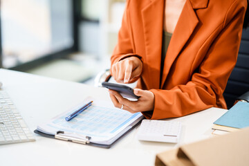 A beautiful Asian businesswoman works at her desk, exuding professionalism and focus.She is deeply...