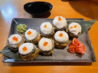 A plated dish featuring crispy tempura rolls topped with whipped cream