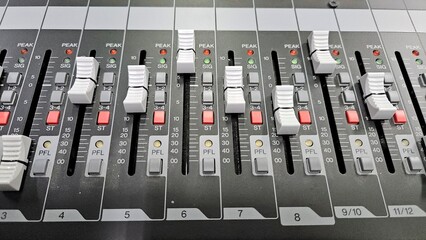 Close-up faders, knos and buttons of audio mixer in broadcast studio.