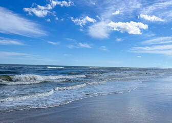 Gentle Waves Meeting the Shore under a Bright Blue Sky