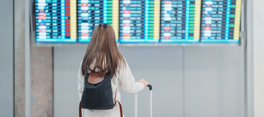 Young woman hand holding luggage handle before checking flight time in airport, Transport,...