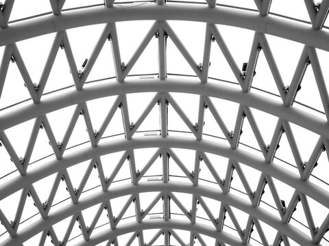 Close-up curved construction on the arch ceiling of bridge of peace, Tbilisi, modern architecture in Georgia. White metal pipes structure supporting roof in building. Abstract curve line background.