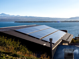 Solar panels on the small industrial factory rooftop near the beautiful lake view background....