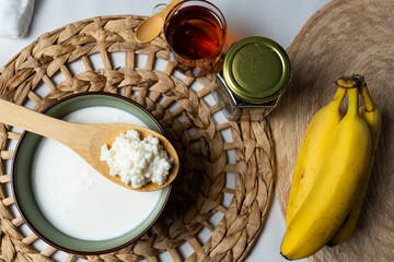 Bebida de kéfir fermentada con probióticos, granos kéfir sobre una cuchara de madera, kéfir preparado con banana. 