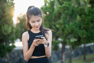 Happy Active healthy asian woman use mobile cell phone exercising with smartphone at urban street outdoors fitness and phone