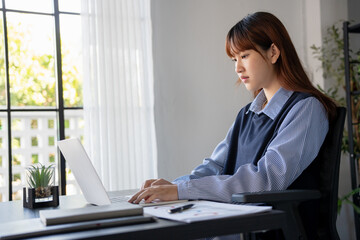 Asian businesswoman using laptop doing documents