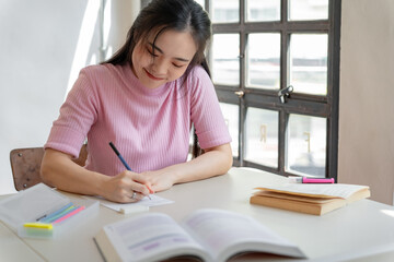 Asian girl student doing exam hand holding pencil writing answer in university classroom education high school or university student taking notes while preparing for exam