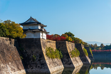 Osaka castle wall and canal at Osaka castle park with autumn leaf foliage.