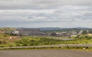 A huge coal mine with buildings, equipment and conveyors and a huge mound of coal set in the...