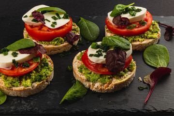 Vegan food, rice cakes with avocado mozzarella spinach onion on a stone board
