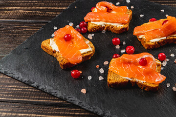 Toasts with butter, mozzarella and salmon on a wooden table for breakfast