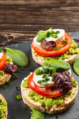Rice cakes with mozzarella, avocado, spinach, onion on a stone on a wooden table