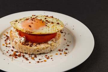 Sandwiches with egg on rice bread on a white plate on a black background closeup