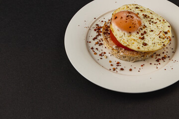 Sandwiches with egg on rice bread on a white plate on a black background closeup