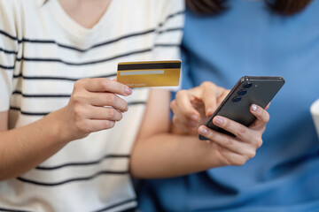 Mother and Child Enjoying Online Shopping Together Using a Smartphone and Credit Card in a Cozy Home Setting