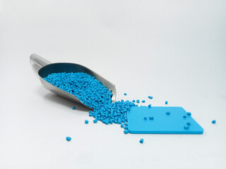 blue masterbatch, polymer carries pigment in stainless steel spoon poured into white background...