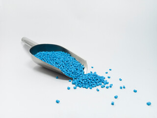 blue masterbatch, polymer carries pigment in stainless steel spoon poured into white background...
