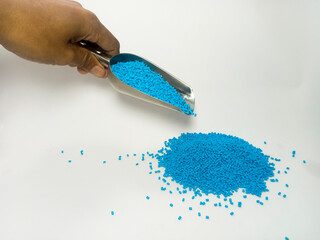 blue masterbatch plastic, pouring masterbatch granules into white background media from a stainless...