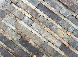 A stone wall with a pattern of brown and gray bricks