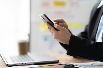 Fototapeta premium Businesswoman Using Smartphone: A close-up shot of a businesswoman's hands holding a smartphone, in a professional setting, highlighting the importance of mobile technology in the workplace. 