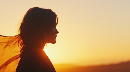 A woman stands elegantly at sunset, her flowing scarf symbolizing strength and unity for gender equality