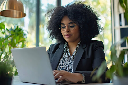 Professional plus-size woman working on a laptop in a bright office
