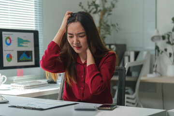 Young businesswoman having neck pain and headache after long working on computer in office, rubbing aching neck and head, suffering from bad posture or sedentary lifestyle