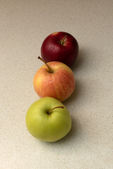 three apples of different colors on the table.