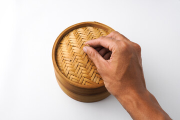 Fototapeta premium Close-up photo of Someone hand is opening wooden dimsum steamer container isolated on white background. Shot on 30 Degree, flat lay angle setup