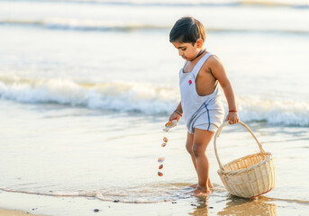 Young asian child collecting seashells on beach