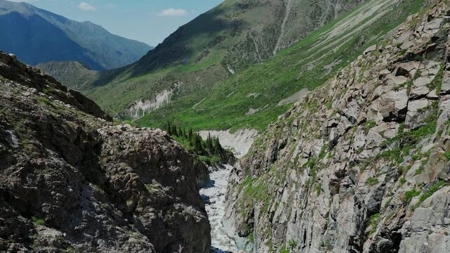 Flight into gorge above river, Kyrgyzstan mountains view. Ala Archa national park near Bishkek. Summer natural landscape, mountain scenery. Popular touristic place for hiking. Aerial drone 4k footage