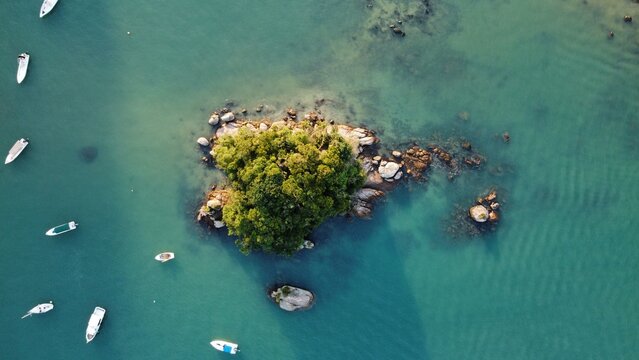 Vue aérienne au drone d'une île paradisiaque avec océan bleu turquoise, paysage littoral calme avec bateau, état de Rio, Ilha Grande, Brésil
