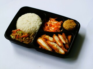 Katsu chicken, rice, noodles, mashed potatoes, vegetable salad, and fritter served on bento box meal isolated white, copy space. Suitable for students and busy worker, home business opprtunity