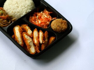 Katsu chicken, rice, noodles, mashed potatoes, vegetable salad, and fritter served on bento box meal isolated white, copy space. Suitable for students and busy worker, home business opprtunity