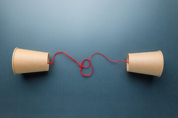 Brown cups phone with red string set on faded background, old style phone, two-way communication