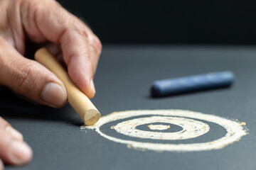 Closeup hand using color pastel chalks to sketch a target on the black paper, create your own...