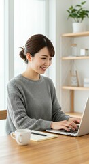 Professional Japanese Freelancer in Her 20s or 30s with Sleek Updo Hairstyle Typing on a Laptop in a Bright Home Office