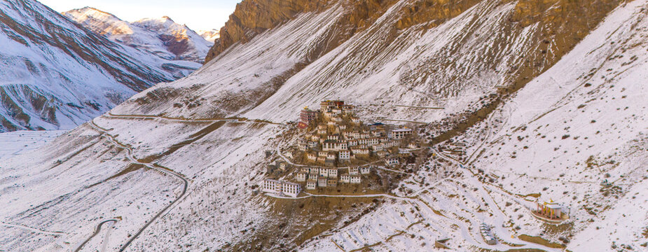 A breathtaking aerial view of Key Monastery perched atop a rugged hill, surrounded by barren, snow-dusted mountains. spiti