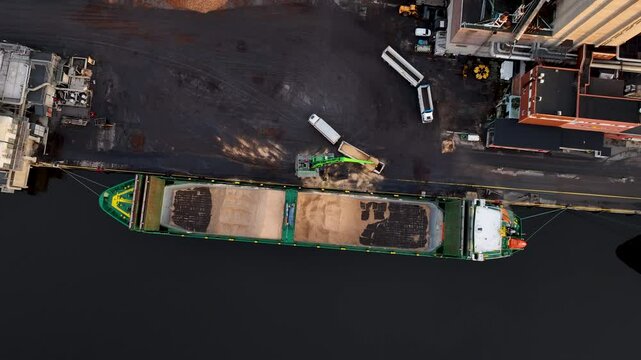 Crane loading wood chips onto barge at port