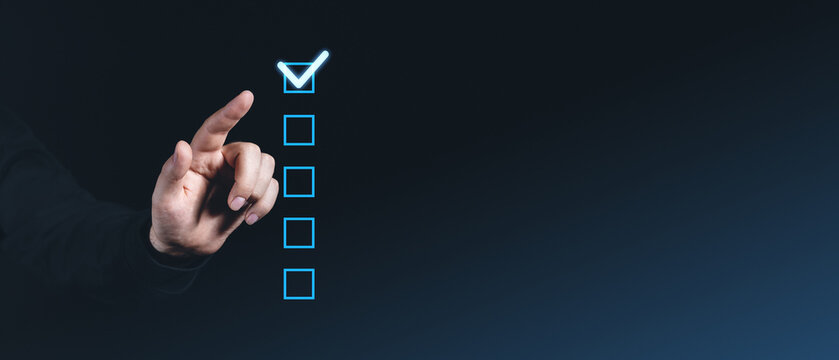 Hand pointing at glowing checkbox on dark background, checklist concept.