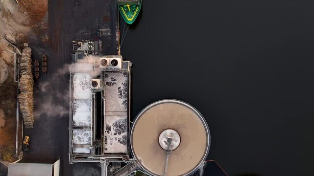Cargo ship docking at paper mill for wood chip delivery