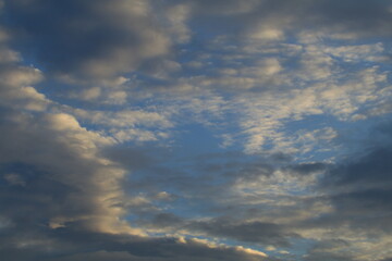The sky is light blue with white and gray clouds. The clouds seem to spread across the sky. The sunlight shines down on the clouds, making them look soft. The sky looks peaceful.