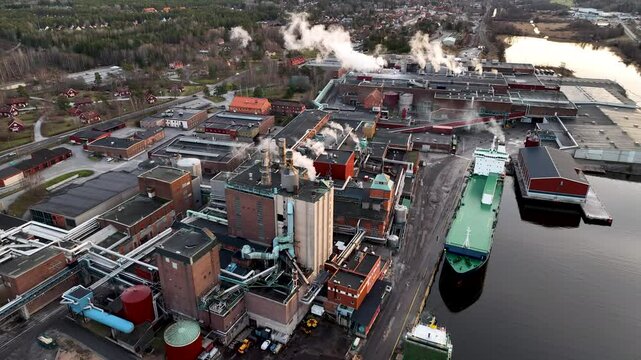 Cargo ship docking at industrial paper mill complex