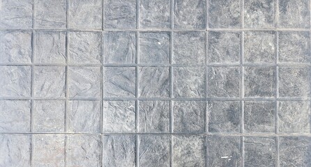 The texture of street ground. Grey square brick pattern. Checkered floor, walkway in the park. Concrete or cement texture, abstract background. 