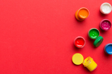 jars with gouache of different colors on Colored background. hobby painting. Top view with empty space. workplace for creativity. home teaching concept drawing