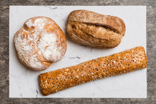 Assortment of freshly baked bread with napkin on rustic table top view. Healthy unleavened bread. French bread
